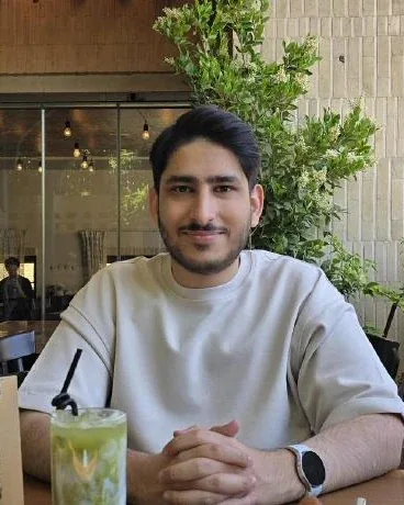 Portrait of Saleh at a café table, a green drink in the foreground